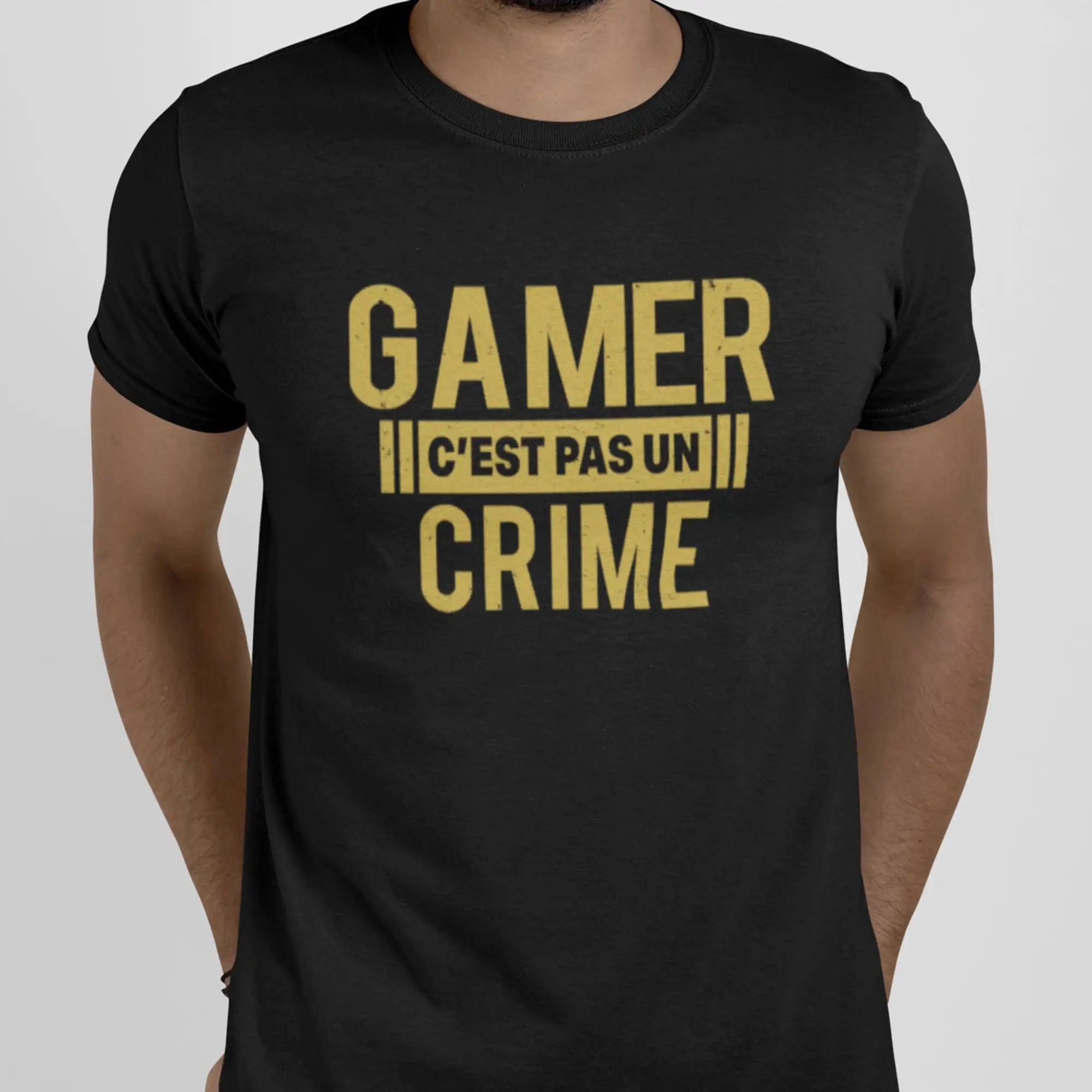 T-shirt noir Ă manches courtes avec du texte jaune audacieux indiquant « gamer câest pas un crime » dans une police usĂ©e.