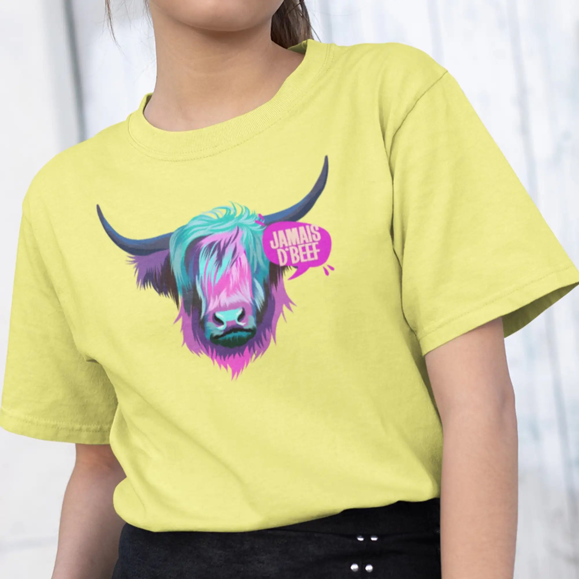 Un t-shirt vibrant jaune Ă manches courtes ornĂ© d'un graphique colorĂ© et stylisĂ© d'une vache des Highlands aux teintes arc-en-ciel et du texte « jamais dâbeff » dans une bulle de dialogue rose.