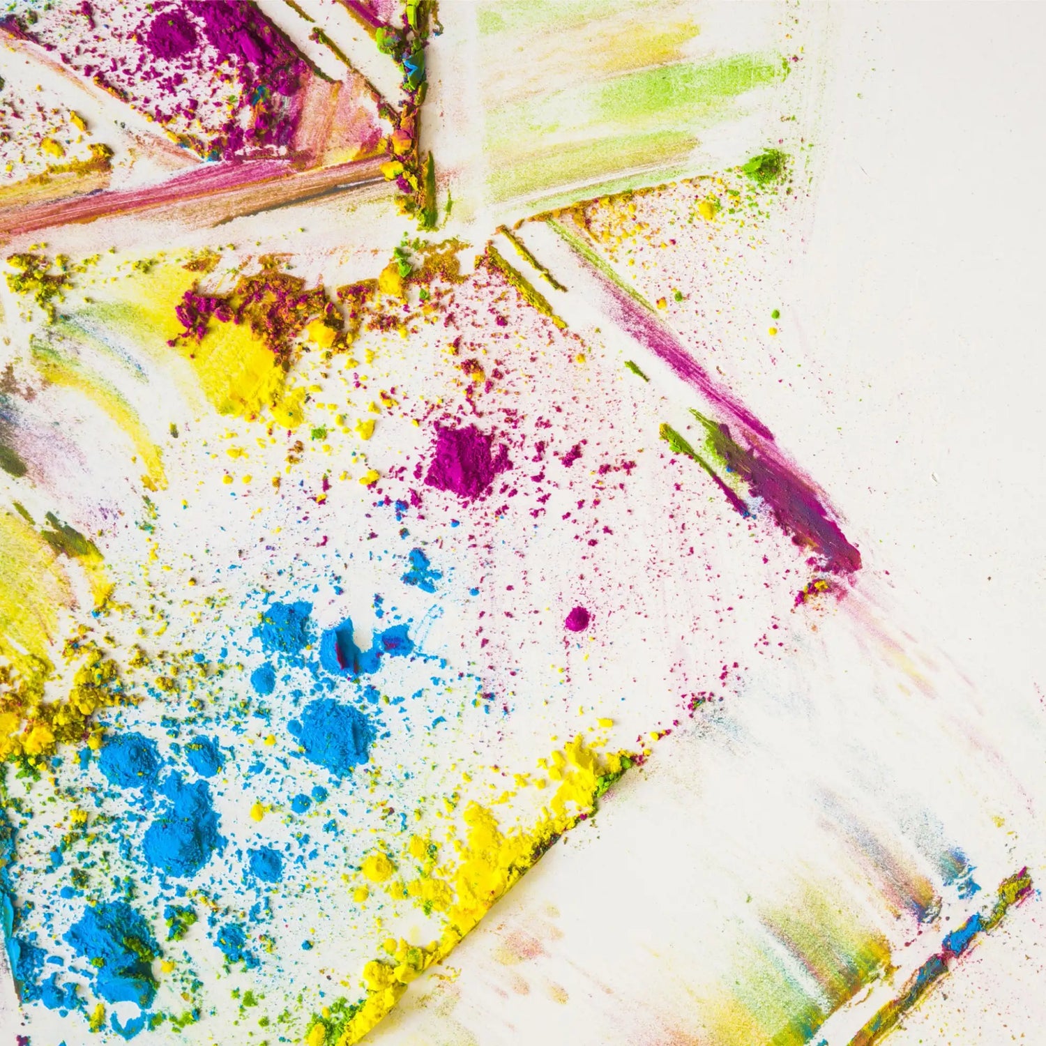 Une coulée de poudre vibrante et multicolore avec des teintes bleu vif, jaune, violet et vert éparpillées sur une surface blanche.