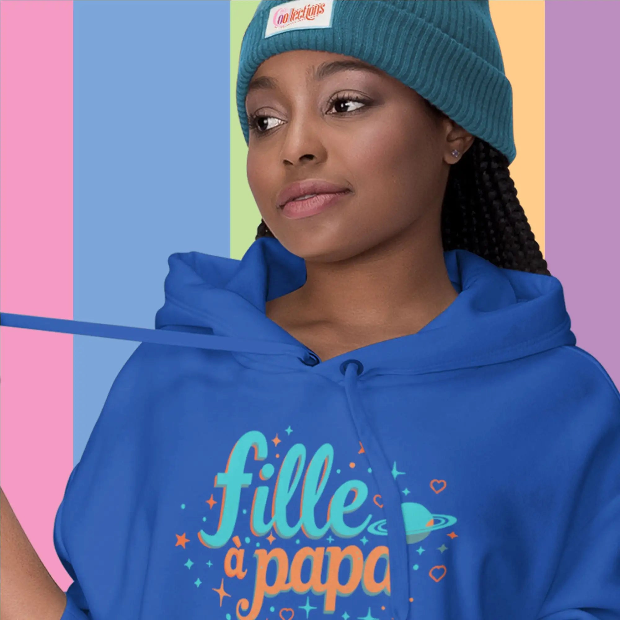 Sweat à capuche bleu avec ‘fille à papa’ imprimé en script turquoise et orange, accentué par des étoiles, des cœurs et un design de planète.