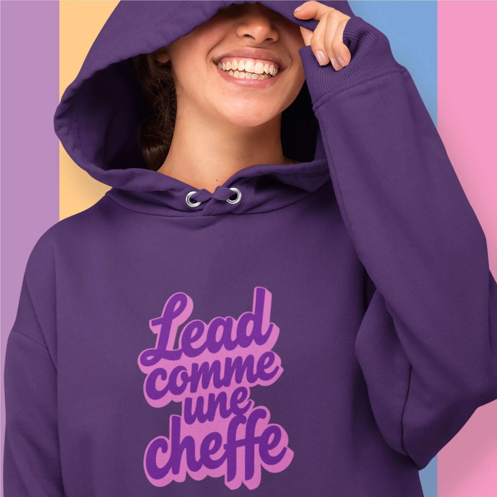 Sweat à capuche violette avec un graphique audacieux violet et rose ’lead comme une cheffe’ imprimé sur la poitrine.