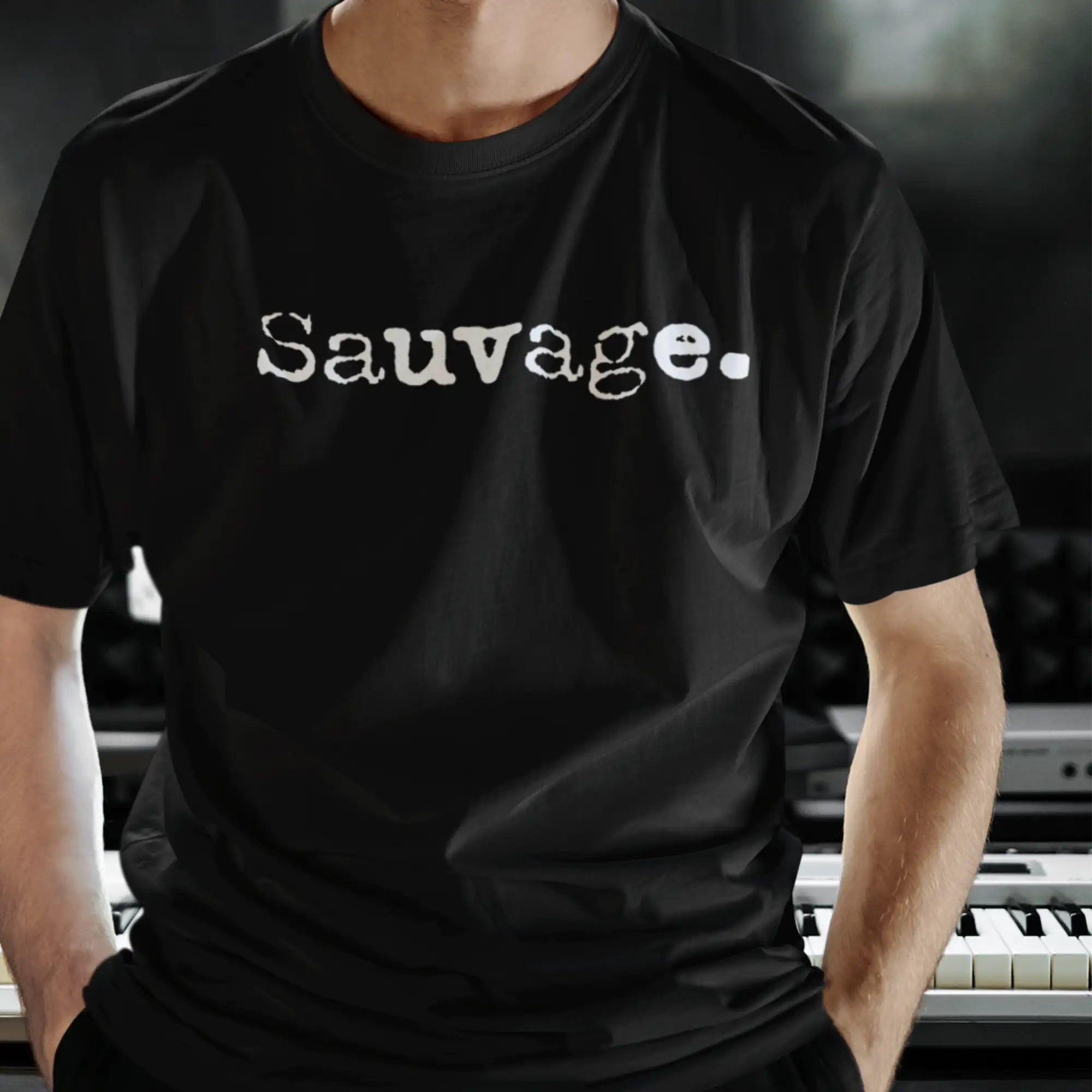 T-shirt en coton noir avec ’sauvage.’ imprimé en police serif blanche sur la poitrine.